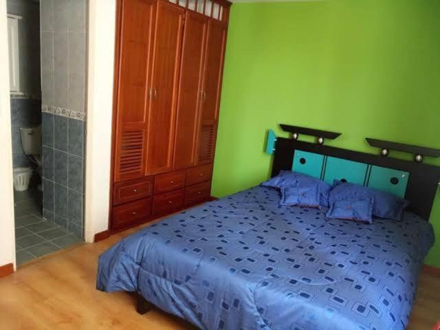 a bedroom with a blue bed and a green wall at Tu descanso in Mexico City