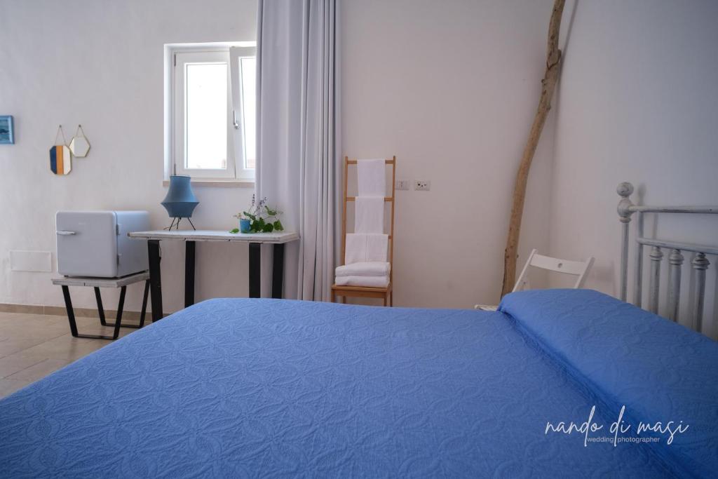 ポリニャーノ・ア・マーレにあるRooms Masseria Giangrandeのベッドルーム(青いベッド1台、窓付)