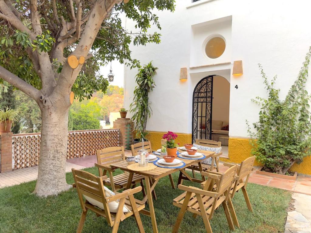 a patio with a table and chairs under a tree at VILLA CLAVERO FOUR Premium Apt in Málaga