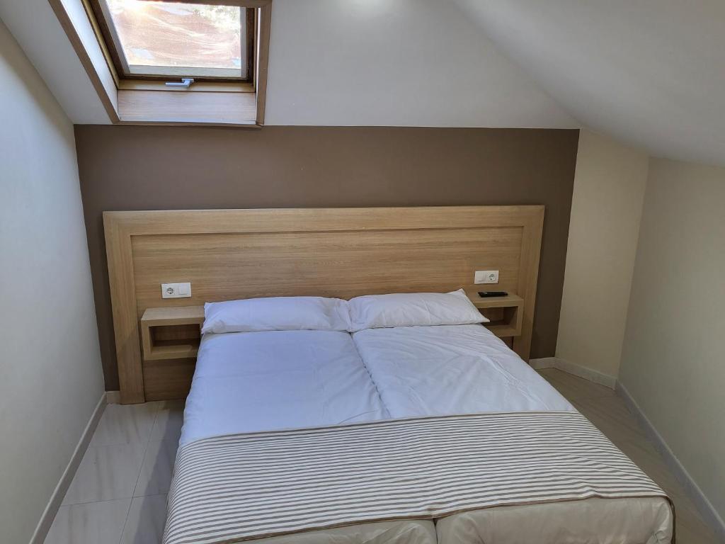 a bed in a small room with a window at CASA MARUXA pensión in Pontevedra