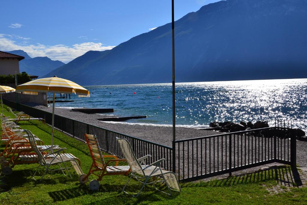 a group of chairs and an umbrella on a beach at Residence San Luigi in Limone sul Garda