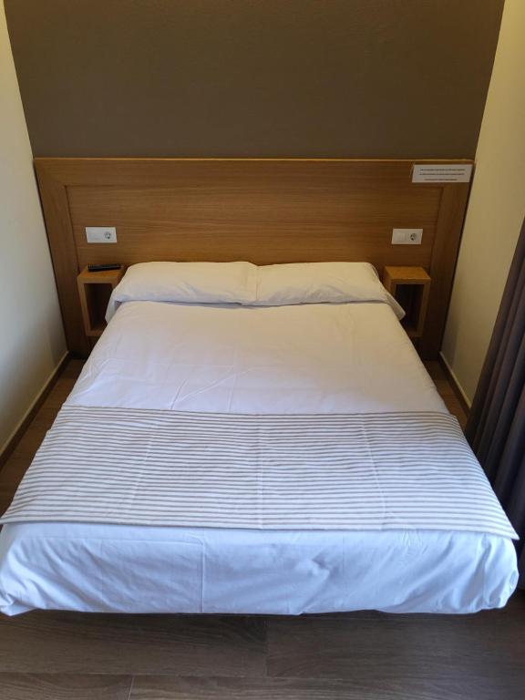 a bed with white sheets and pillows in a room at CASA MARUXA pensión in Pontevedra