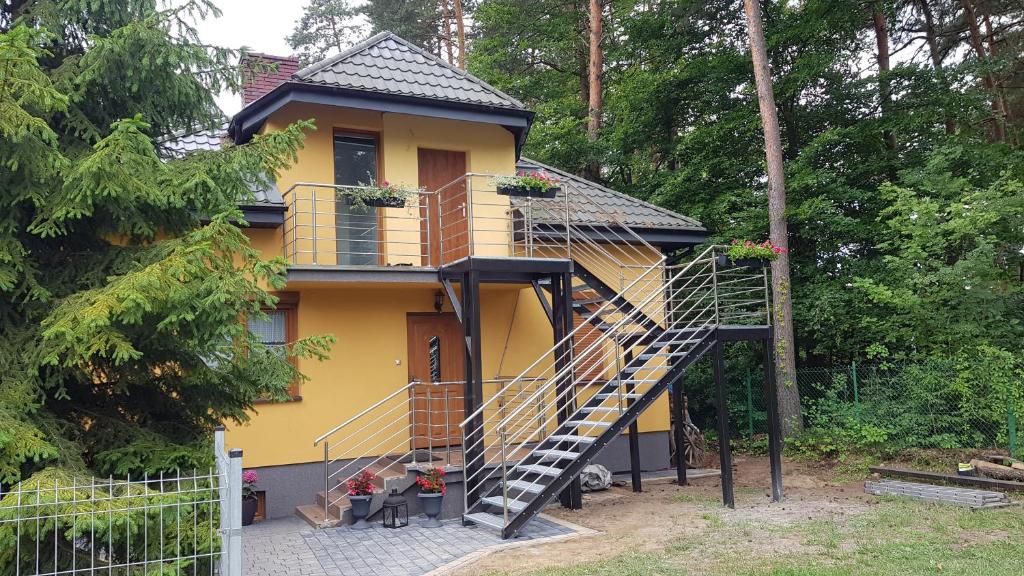 ein gelbes Haus mit einer Wendeltreppe davor in der Unterkunft Apartament Sosnowa in Krasnobród