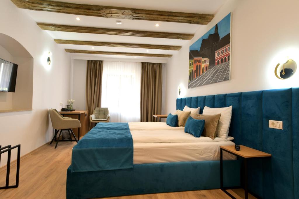 een hotelkamer met een groot bed met een blauw hoofdeinde bij Prinz Gregor in Braşov