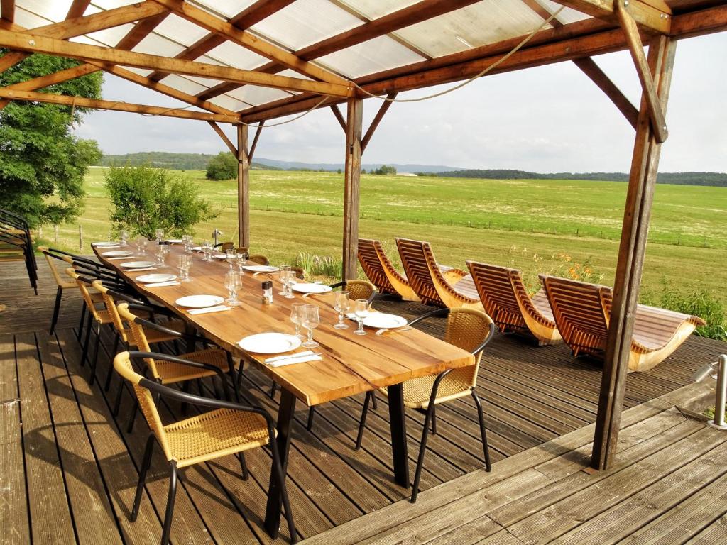a long wooden table and chairs on a deck at ferme du bois joli in Marigny