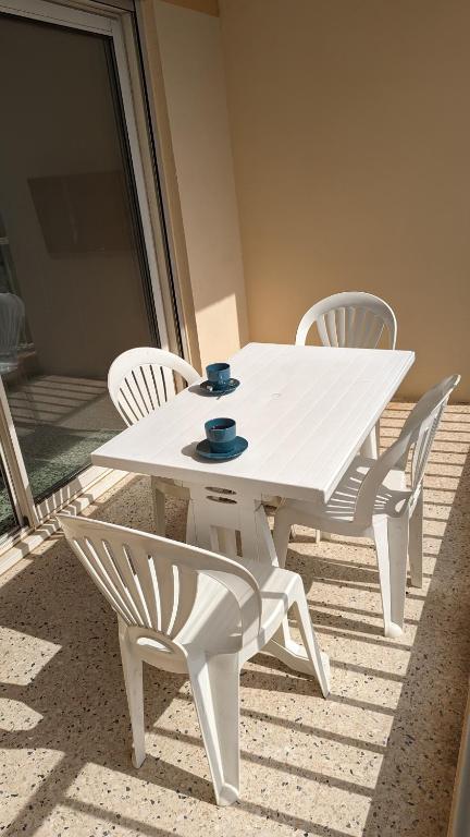 une table blanche et des chaises sur une terrasse dans l'établissement Studio climatisé avec coin nuit 150m de la plage, au Lavandou