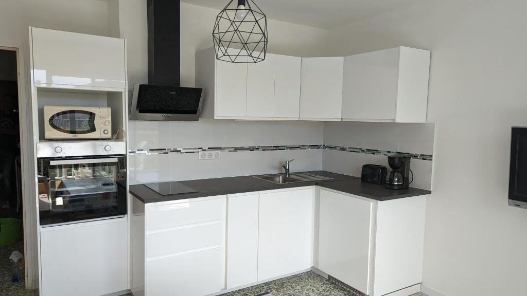 a white kitchen with a sink and a microwave at Studio avec coin nuit 150m de la plage in Le Lavandou