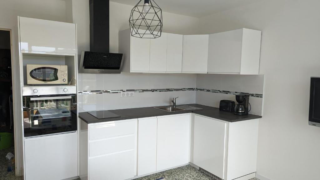 a white kitchen with a sink and a microwave at Studio climatisé avec coin nuit 150m de la plage in Le Lavandou