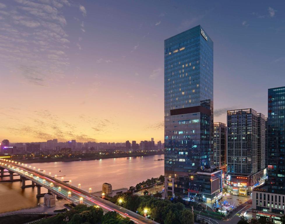 a city skyline with a tall building and a river at Hilton Zhuzhou in Zhuzhou