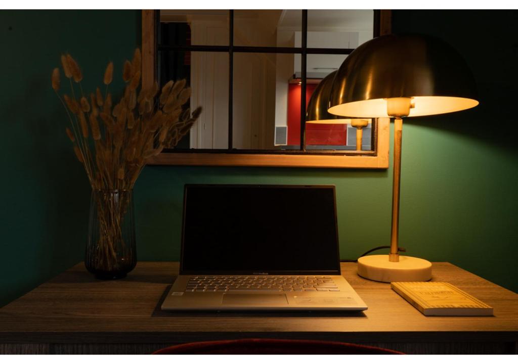 a laptop computer sitting on a desk with a lamp at Le Cocon de la Cathédrale - Hypercentre Evreux - Jungle Chic - Vue sur l'Iton et Cathédrale in Évreux
