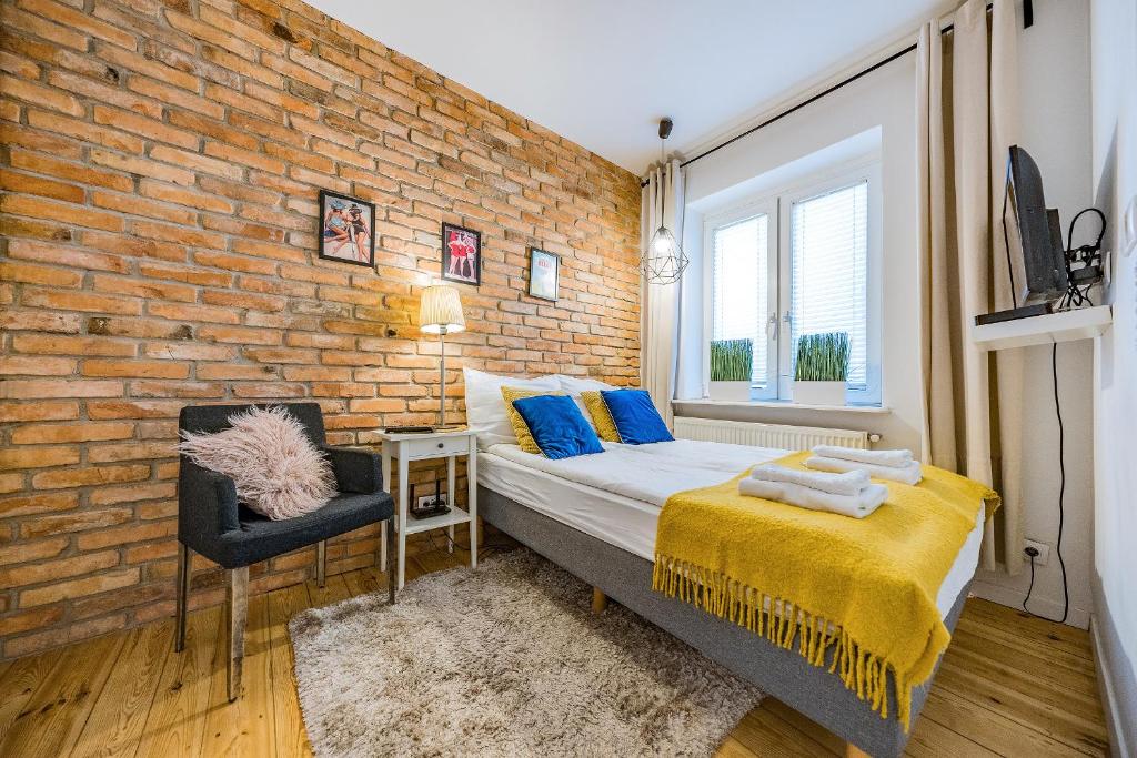 a bedroom with a brick wall and a bed and a chair at Pomorskie Apartamenty Enter House in Sopot