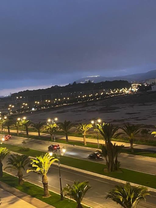 a street with palm trees and a city at night at Appartement Anir in Agadir