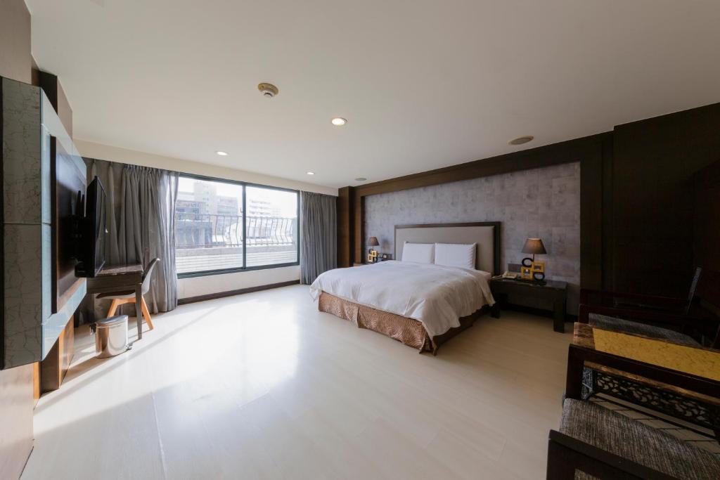 a large bedroom with a bed and a large window at Shihzuwan Hotel – Kaohsiung Station in Kaohsiung