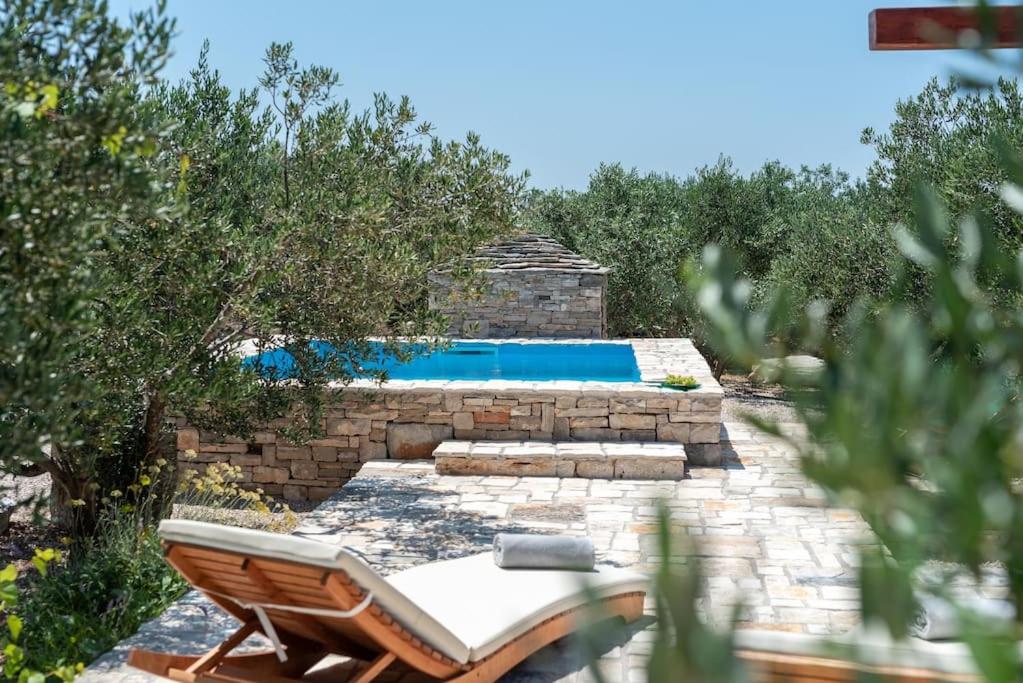 a chair and a swimming pool in a yard at Trapula stone paradise in Maslinica