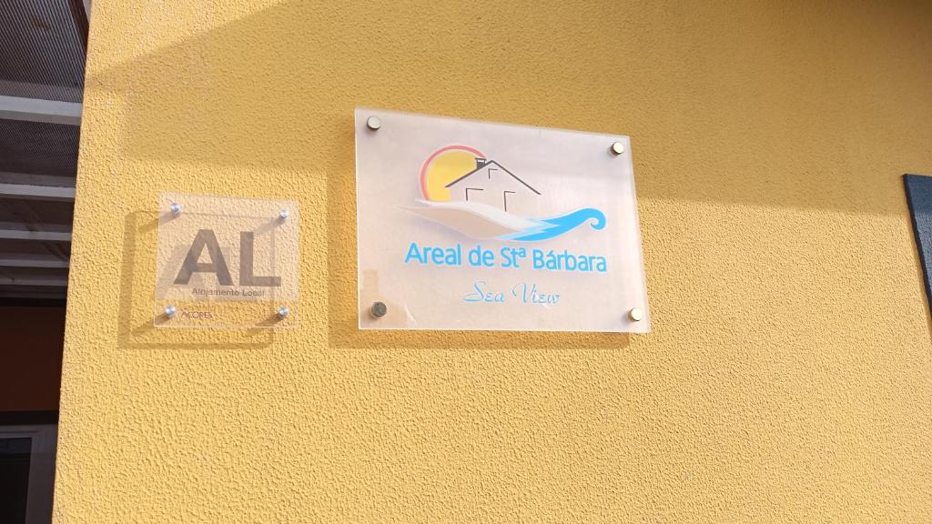 una señal en el costado de una pared amarilla en Areal de Santa Bárbara Sea View, en Ribeira Grande