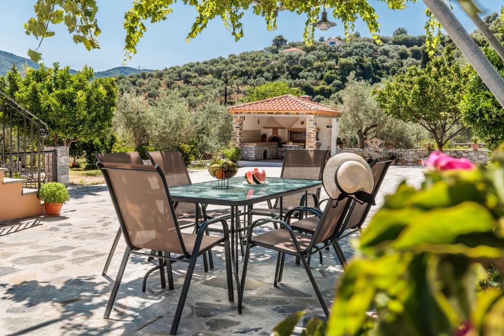 un patio con mesa, sillas y cenador en Glyna House, en Skopelos Town