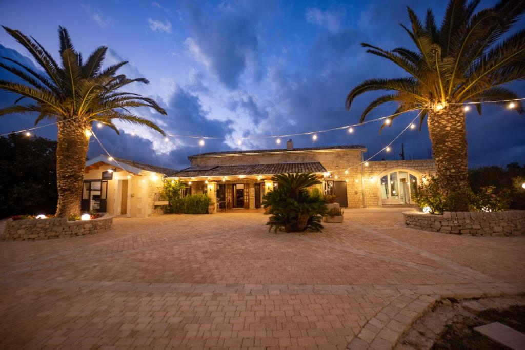 a building with two palm trees and lights at Casale Della Contea in Modica