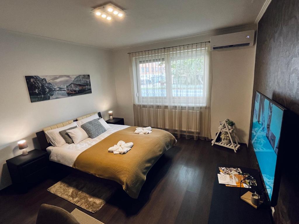 a bedroom with a large bed and a flat screen tv at Borisz Apartman in Makó