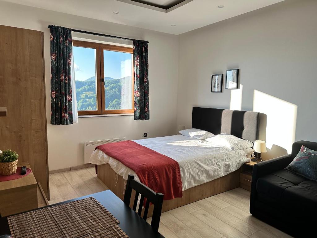 a bedroom with a bed and a couch and a window at Nana S44 Milmari Spa&Wellness in Kopaonik