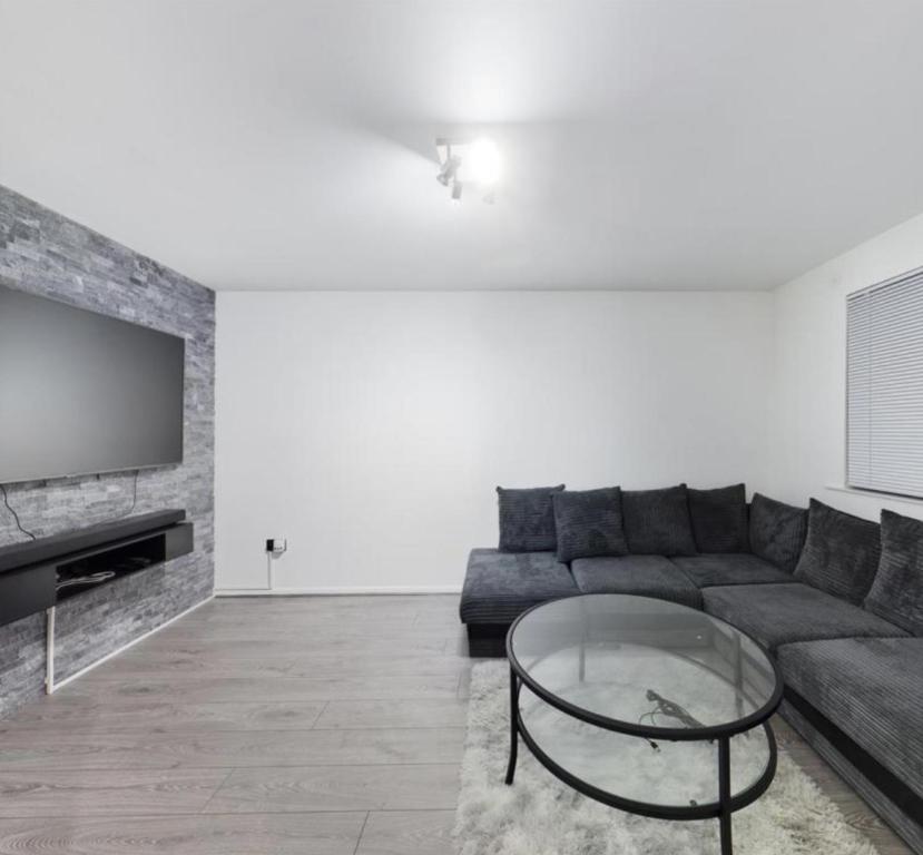un soggiorno con divano e tavolo in vetro di Grays Serviced Apartment a Stifford