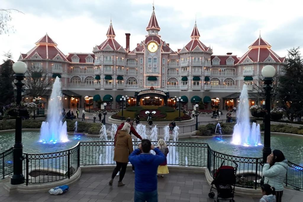 un groupe de personnes debout devant un bâtiment avec des fontaines dans l'établissement Paradise - Disneyland Paris, à Chessy