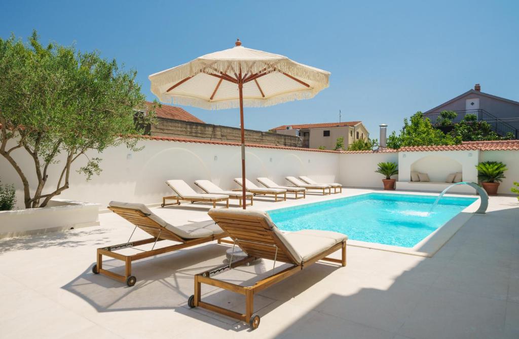 a pool with lounge chairs and an umbrella and a swimming pool at Villa Bianca Vodice in Vodice