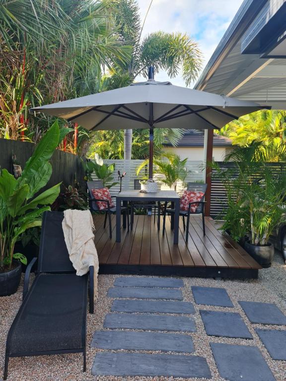 a wooden deck with a table and an umbrella at Blue Lagoon Tropical Sanctuary in Trinity Beach