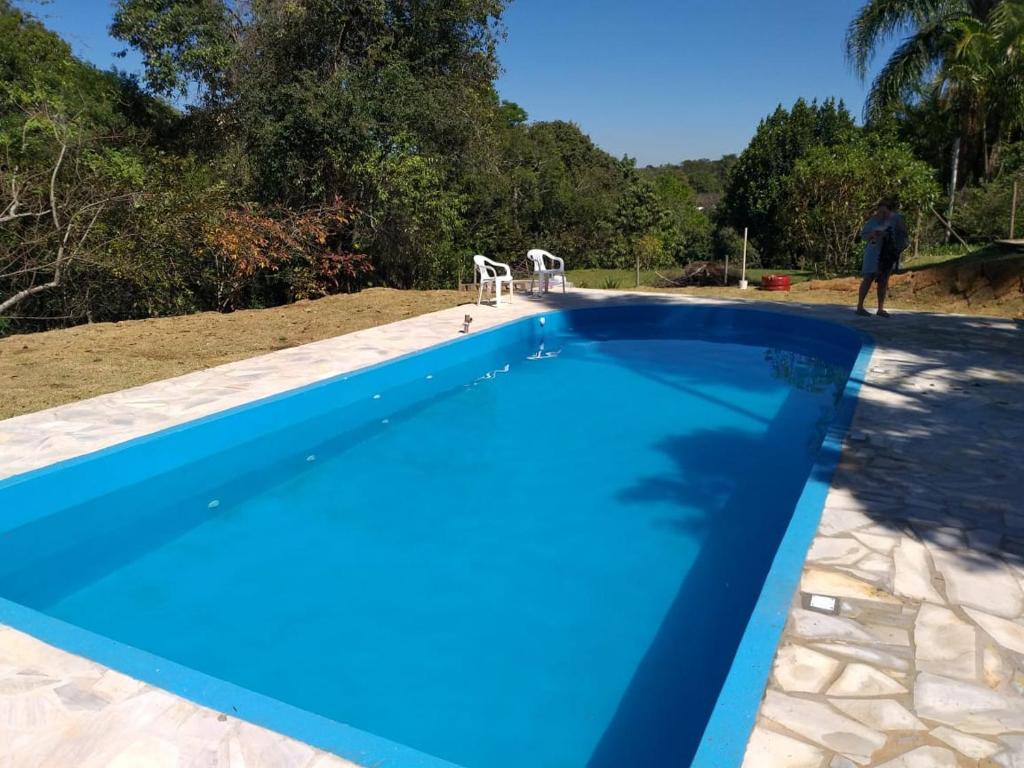 un hombre de pie junto a una piscina azul en Chacara Vale dos Sonhos Itu, en Itu