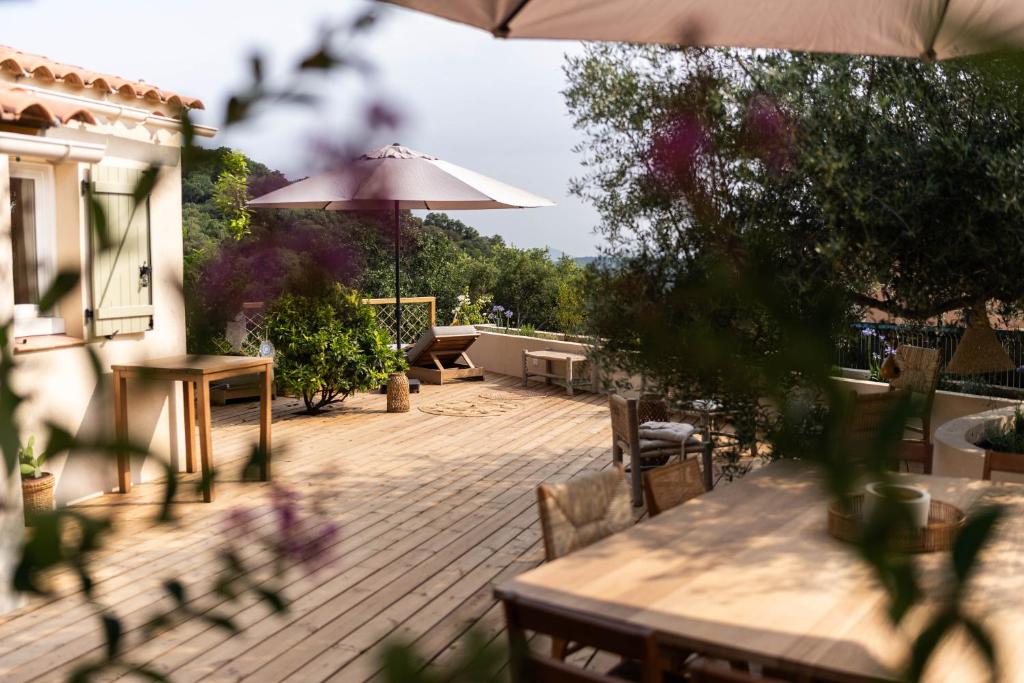 a patio with tables and chairs and an umbrella at Maison Calie #Ramatuelle #Nature #Vue Mer in Ramatuelle