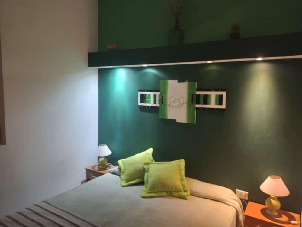 1 dormitorio con 1 cama con pared verde en Departamentos del Puerto Verde en Paraná