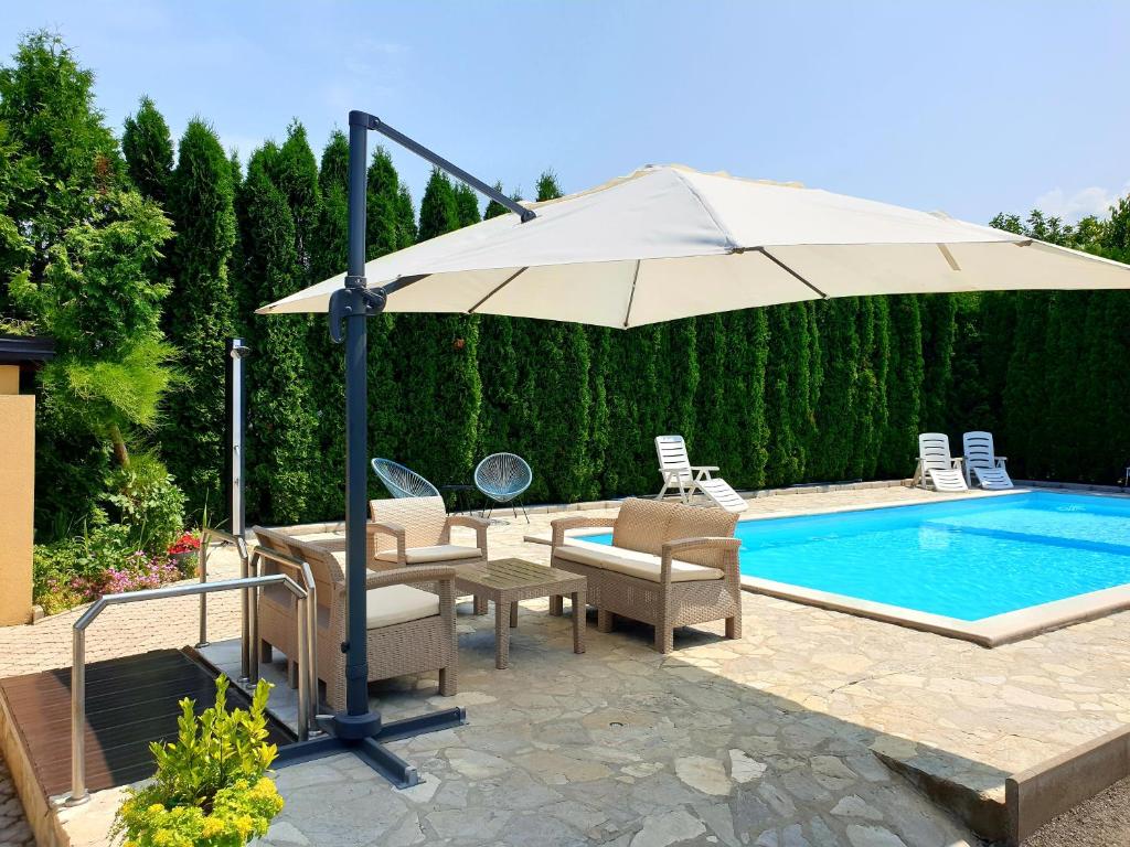 un patio con sombrilla, sillas y piscina en Natural Cottage Una, en Bihać