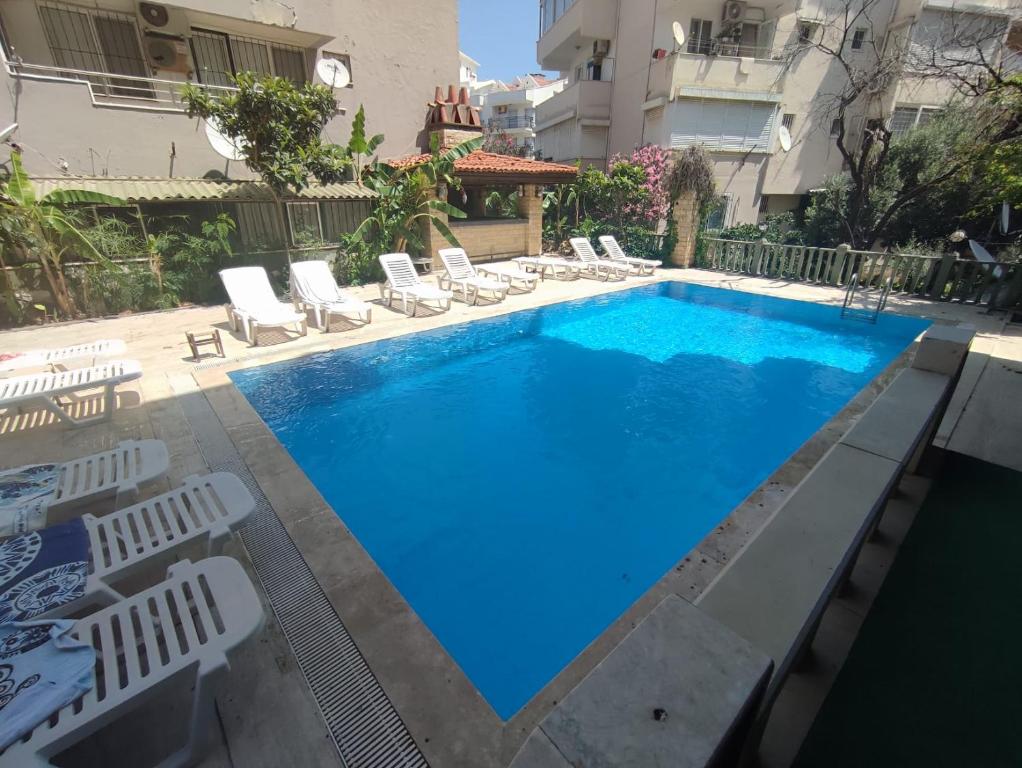 a large swimming pool with lounge chairs next to a building at Antik Apartments Marmaris in Marmaris