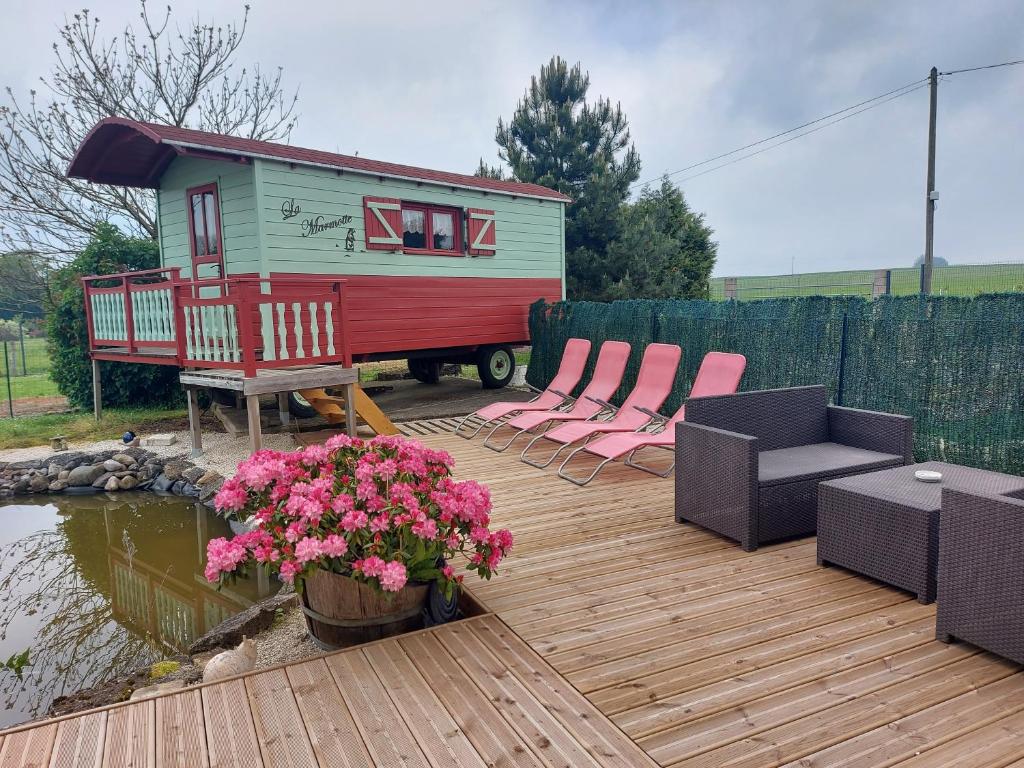 eine Terrasse mit Stühlen und ein kleines Haus in der Unterkunft Roulotte La Marmotte in Poinson-lès-Fays