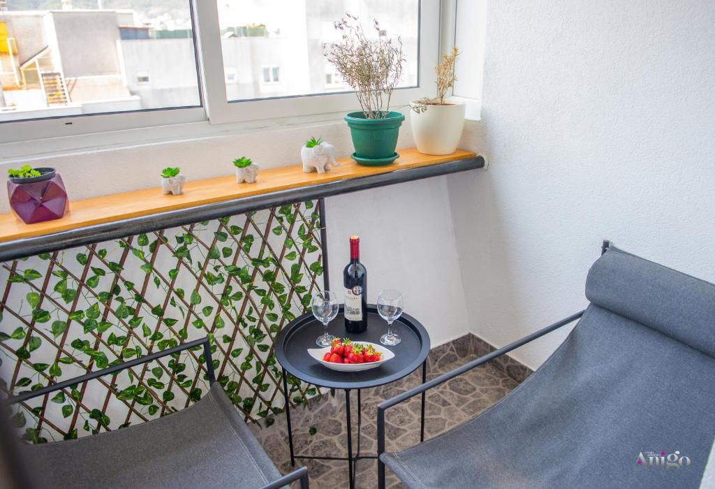a table with a bottle of wine and a bowl of fruit on a balcony at Central Loft in Mostar