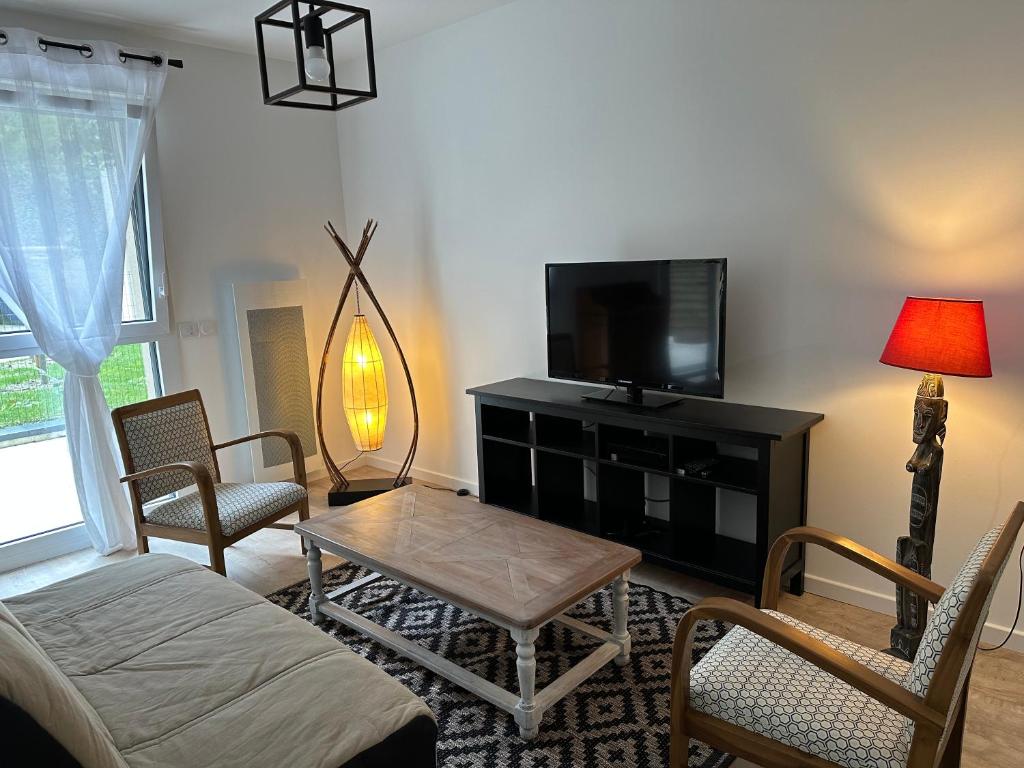 a living room with a tv and a table and chairs at L'Aumonerie in Angers