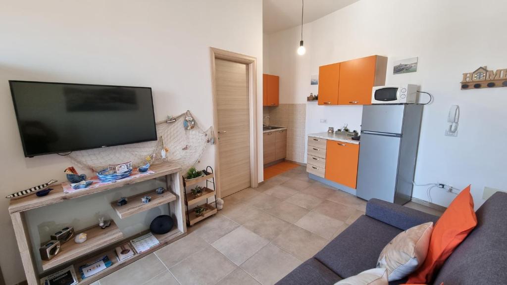 sala de estar con TV y cocina en Appartamento Tharros, en Cabras