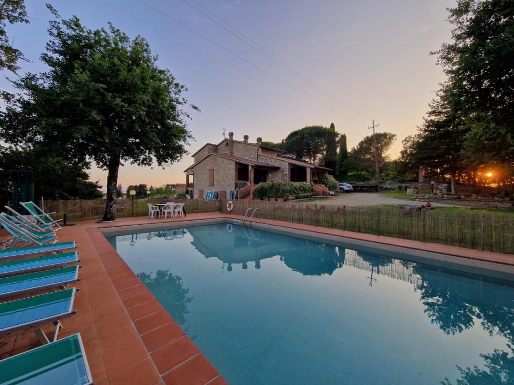 uma piscina com cadeiras e uma casa ao fundo em Villa Orizzonte em Castelnuovo Berardenga