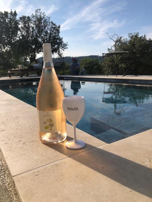 a bottle of wine with a glass next to a swimming pool at VILLA avec PISCINE PRIVÉE NON PARTAGÉE in Camps-la-Source