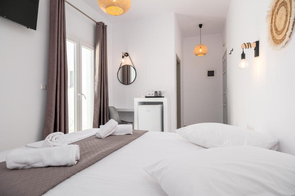 a white bedroom with a large bed and a mirror at ALTHEA PAROS in Naousa