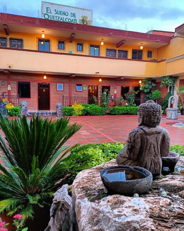 a statue sitting on a rock in front of a building at El Sueño de Quetzalcoatl in San Juan Teotihuacán
