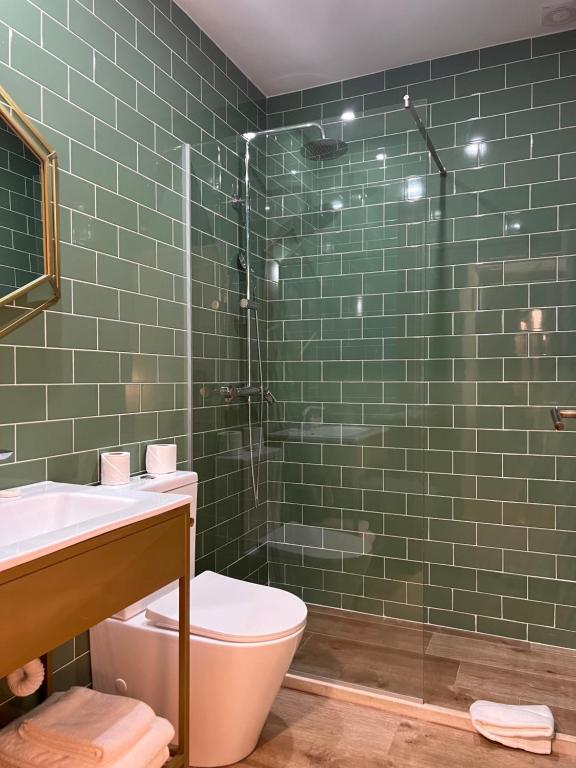 y baño de azulejos verdes con aseo y ducha. en 145 Townhouse, en Ílhavo
