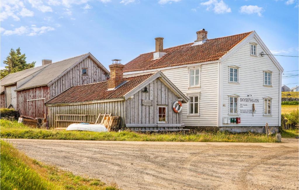 an old white house with a barn on a dirt road at Beautiful Apartment In Vanse With House Sea View in Vanse