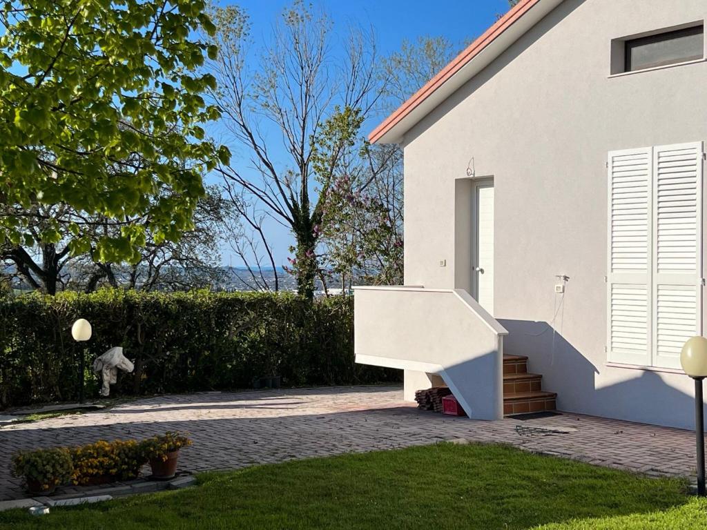una casa blanca con una escalera junto a un patio en Casa Tullo, en San Costanzo