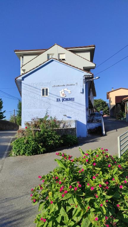 un edificio blanco con flores rosas delante en Apartamentos El Jornu, en Llanes