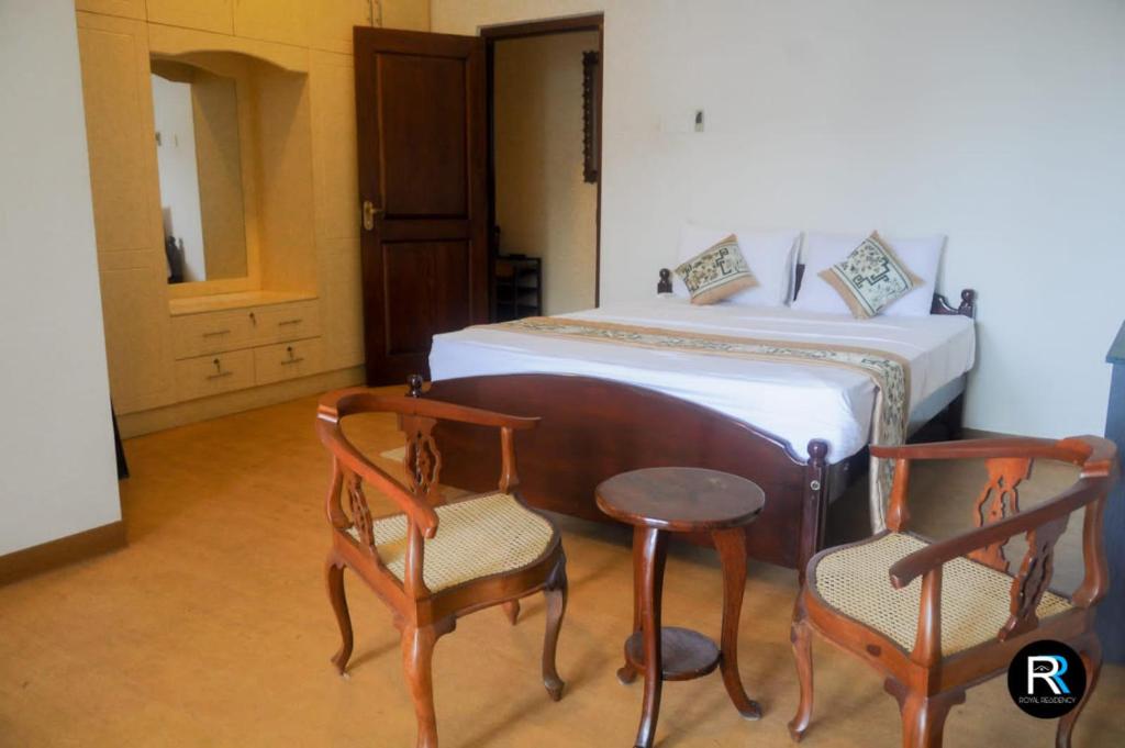 a bedroom with a bed and two chairs and a table at Royal Residency in Kandy