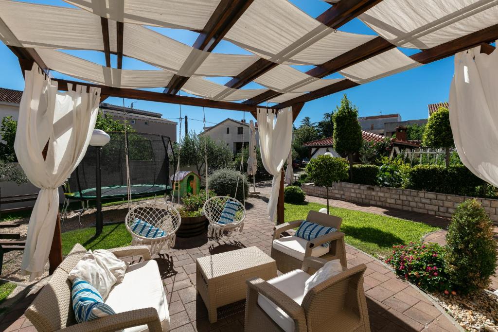 un patio con pérgola de madera y sillas en Pansion Gaspar, en Biograd na Moru