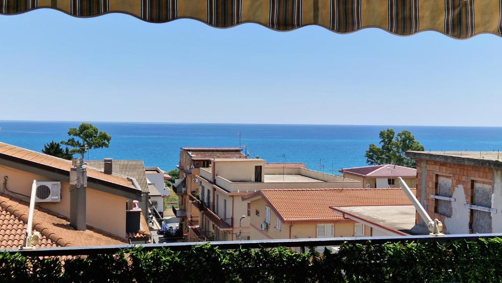een stad met gebouwen en de oceaan op de achtergrond bij Blue Horizon Calabria - Seaside Apartment 120m to the Beach - Air conditioning - Wi-Fi - View - Free Parking in Santa Caterina Dello Ionio Marina
