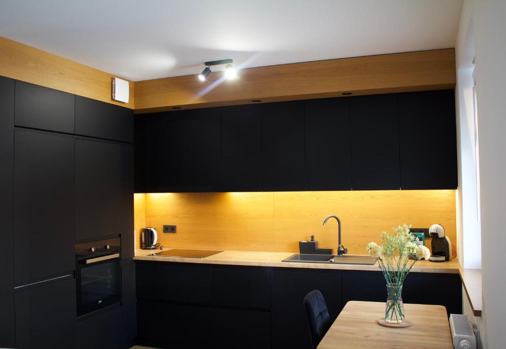 a kitchen with black cabinets and a table with flowers on it at K&M Apartament Panorama in Bochnia