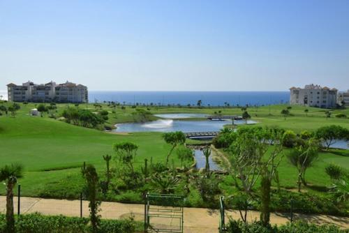 a view of a golf course with the ocean in the background at Asilah Marina Golf in Asilah
