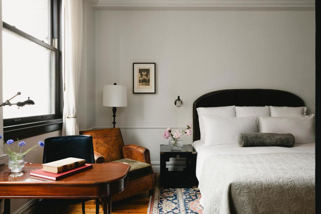 a bedroom with a bed and a desk and a table with a chair at The Ned NoMad in New York